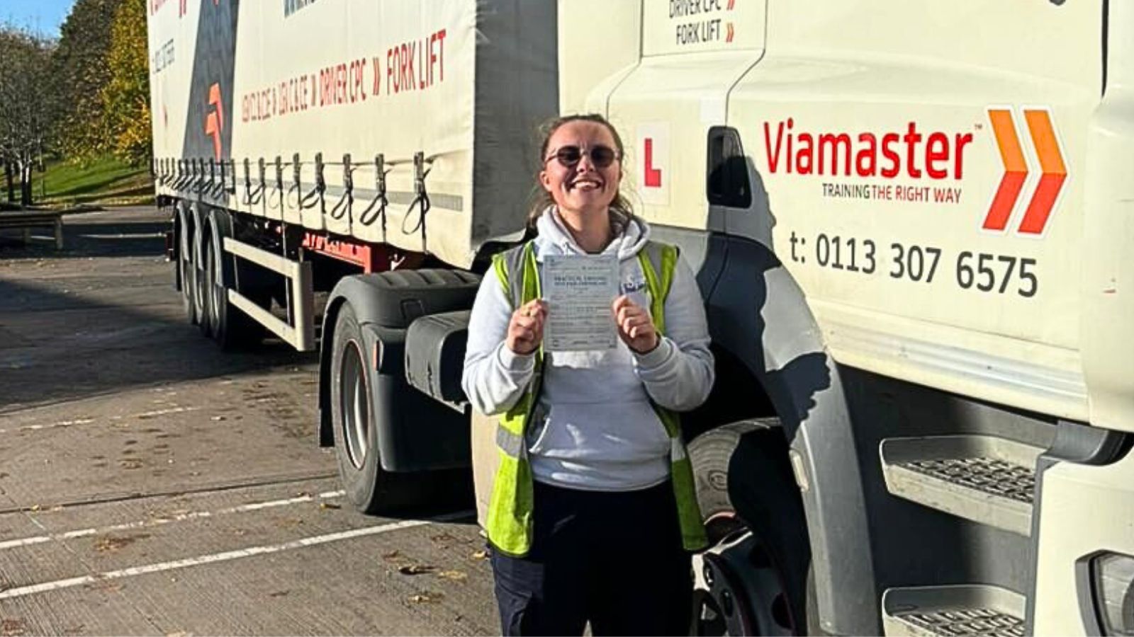 Bethany shows off her certificate in front of one of the HGVs
